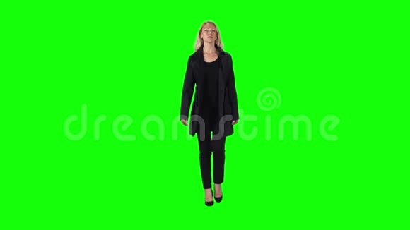 金发女孩穿着黑色外套裤子和高跟鞋穿着绿色的屏幕慢动作视频的预览图