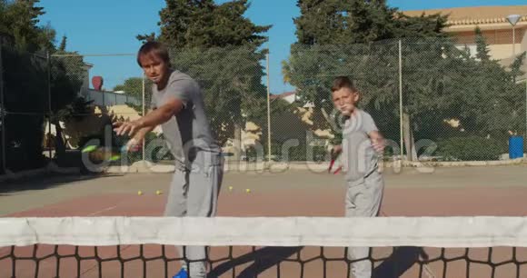 打网球的孩子父亲和儿子练习打网球一起积极休闲视频的预览图