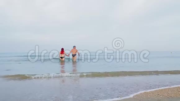 一男一女牵着手走在海水上视频的预览图