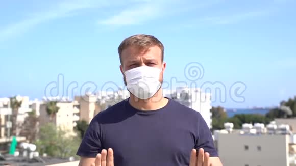 千禧年白种白人男性戴着医用口罩的肖像显示停止手势信号视频的预览图
