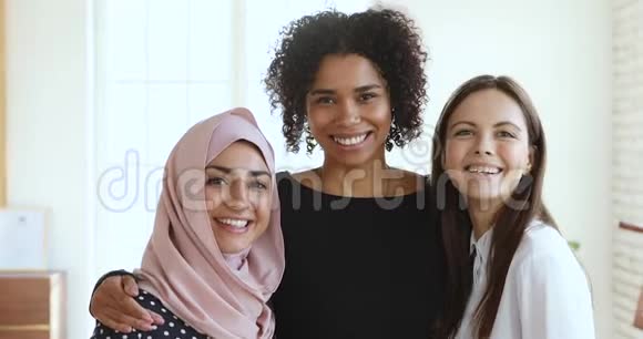 三个多文化的微笑年轻女性朋友拥抱看镜头视频的预览图