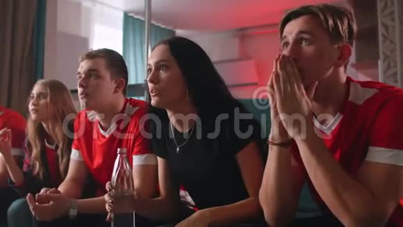 一群球迷坐在客厅的沙发上在电视上观看足球比赛庆祝进球视频的预览图