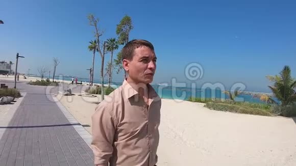 一个成年男子沿着人行道沿着海滩散步视频的预览图