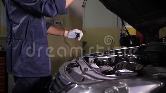 汽车机械师用手电筒看引擎盖下视频的预览图