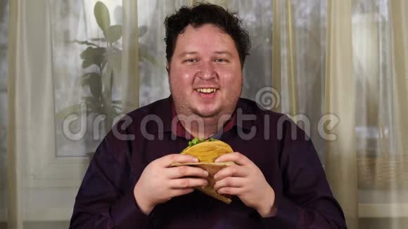 年轻人拿着三明治胖子吃快餐玉米饼不是有用的食物很饿的家伙视频的预览图