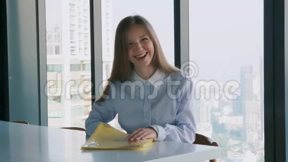 微笑的年轻女商人独自坐在办公室看着镜头视频的预览图