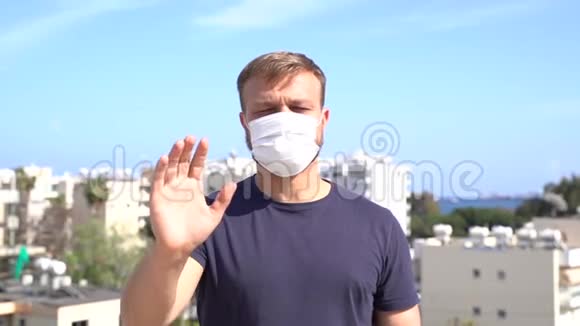 千禧年白种白人男性戴着医用口罩的肖像显示停止手势信号视频的预览图