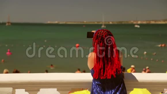 一个穿着蓝色裙子的快活女人从海滨拍海视频的预览图