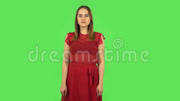 穿着红色衣服的温柔女孩微笑着用手指露出心然后吹吻绿色屏幕视频的预览图