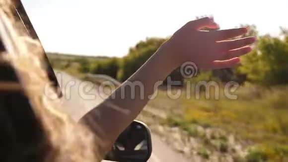 自由的女人乘汽车旅行用她的手从车窗里抓住了风长发女孩坐在前面视频的预览图