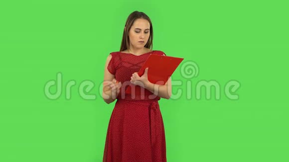 穿红色衣服的温柔女孩用pensil把文件填在红色文件夹里绿色屏幕视频的预览图