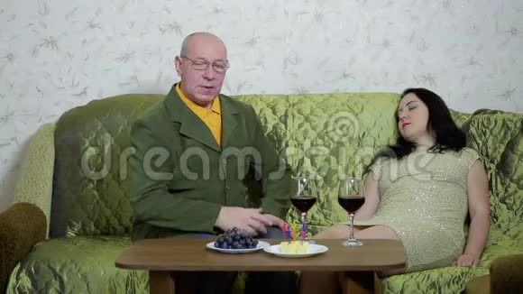 一对相爱的幸福夫妇坐在桌子旁的沙发上喝红酒视频的预览图