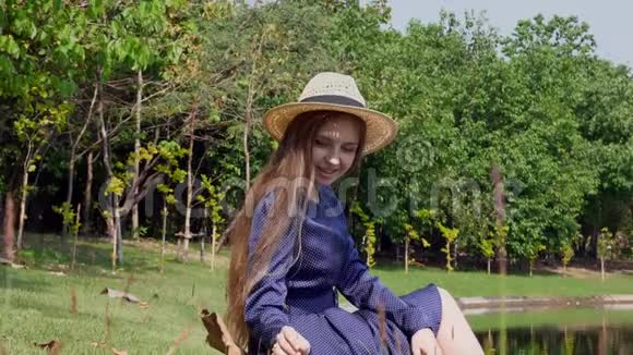 快乐女孩坐在湖边触摸草地自然放松和休闲视频的预览图
