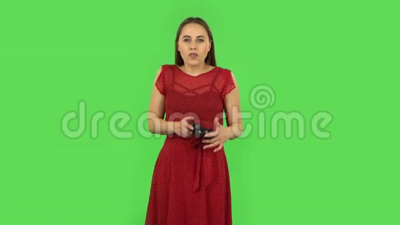 穿红色衣服的温柔女孩正在使用无线控制器玩电子游戏然后输了绿色屏幕视频的预览图