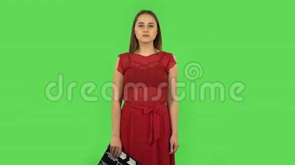 穿红色裙子的温柔女孩手里拿着一部电影绿色屏幕视频的预览图