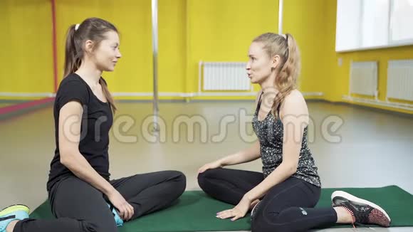 两位年轻的女性朋友在演播室里微笑着聊天并在训练结束后给五个人友谊积极的生活方式和运动视频的预览图
