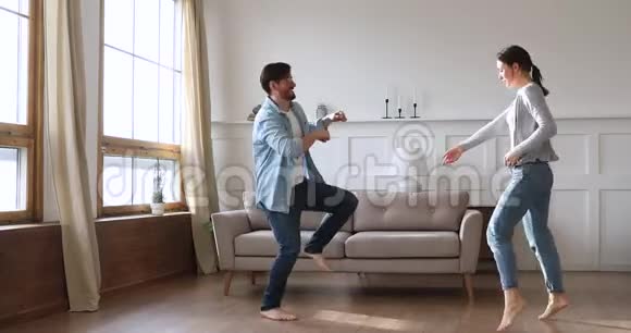 快乐无忧无虑的年轻夫妇一起在客厅跳舞视频的预览图