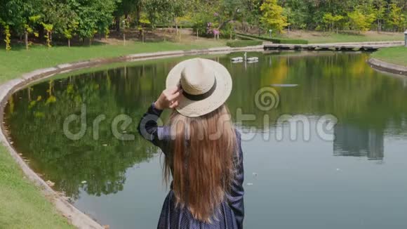 热带夏季公园里女性站在湖边视频的预览图