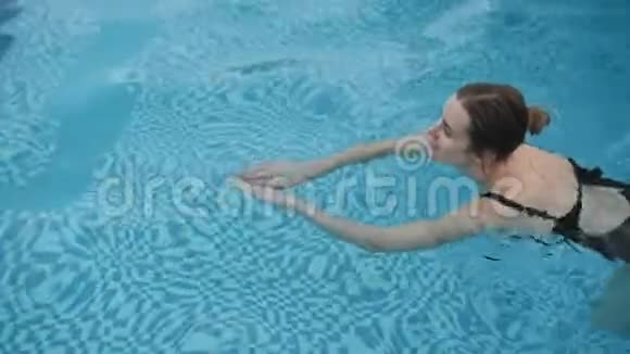 穿黑色泳衣的可爱女孩在游泳池里游泳视频的预览图