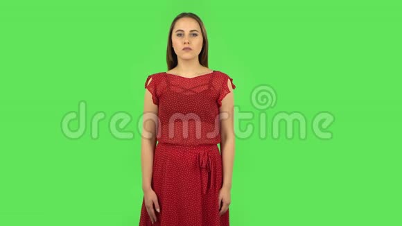 红衣嫩嫩的女孩正听着信息震惊而又微笑绿色屏幕视频的预览图