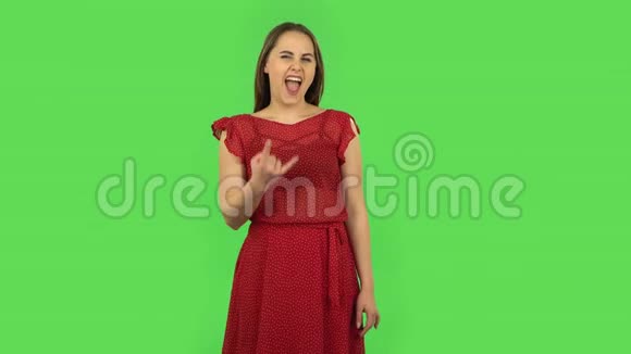 穿着红色裙子的温柔女孩在做一个摇滚手势享受生活绿色屏幕视频的预览图