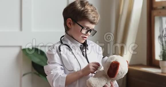 有趣的学龄前儿童穿着医用外套拿着听诊器听玩具视频的预览图