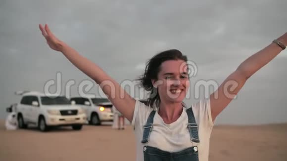 在阿拉伯联合酋长国一辆沙漠旅游观光车的背景上摆着一个快乐的女孩视频的预览图