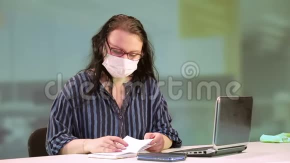 办公室里的一名妇女戴着医疗面罩工作视频的预览图
