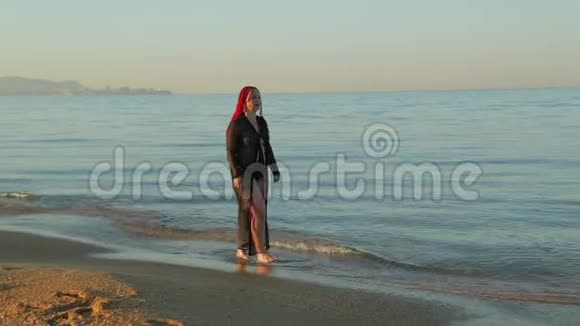 一个穿着泳衣穿着黑袍的女人在海边散步视频的预览图