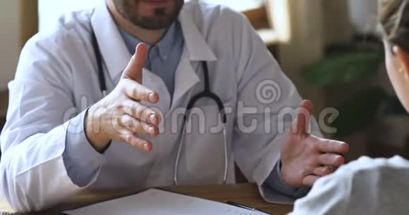 男性医生在医疗预约时与女性患者握手特写视频的预览图