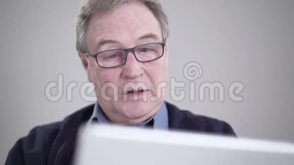 上了年纪的白种人男人的特写脸在平板电脑上看着自拍相机有感情地笑着现代视频的预览图