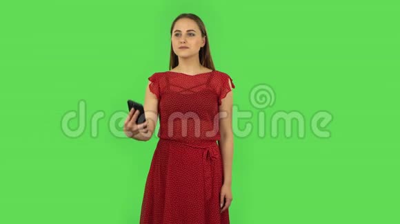 穿红色衣服的温柔女孩正在用手机聊天视频并感到欣喜绿色屏幕视频的预览图