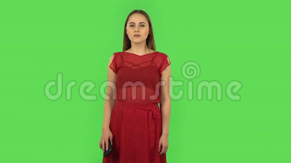 穿红色裙子的温柔女孩正通过电话在网络上询问信息绿色屏幕视频的预览图