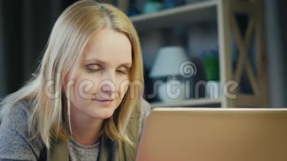漂亮的中年妇女在房间里用笔记本电脑工作视频的预览图