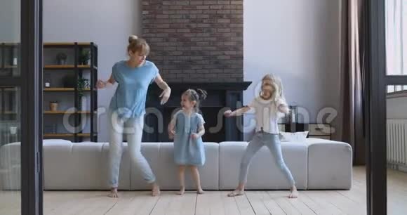 快乐的年轻女子和欣喜若狂的女儿在客厅跳舞视频的预览图