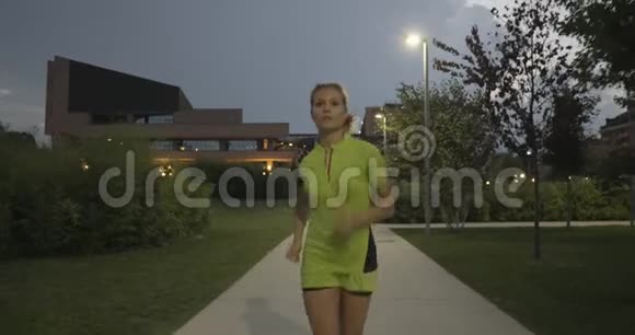 健身的金发女人穿着公园人行道上的跑步训练前面是下面的视图夏天的晚上或晚上工业视频的预览图