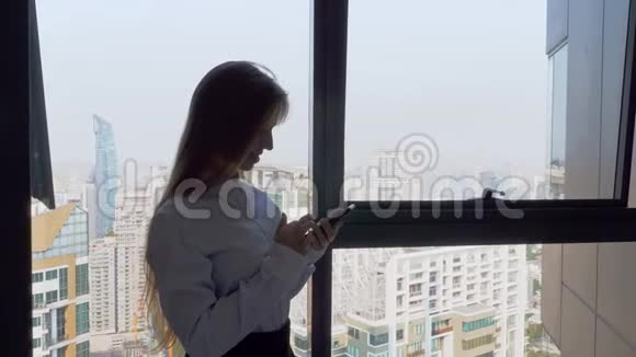 女商人站在办公室在窗口附近工作可以看到城市景色视频的预览图