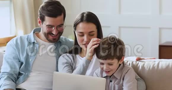 轻松三口之家使用笔记本电脑坐在沙发上视频的预览图