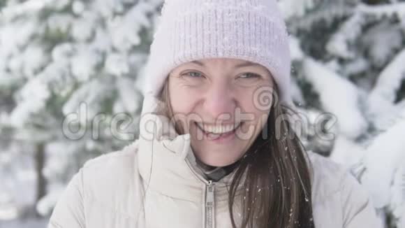 一个女人在白雪皑皑的冬林中的特写视频的预览图