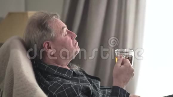 高级白种人老人在摇椅上摇摆喝着茶积极的高级男性退休者挥手的侧视视频的预览图