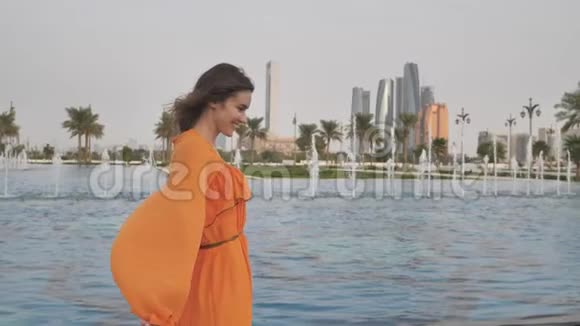 一个穿着橙色连衣裙的女孩走过傍晚的阿布扎比阿联酋视频的预览图