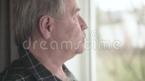 近景侧面的成熟白种人男子看窗外高级男性退休人员室内肖像老龄化视频的预览图