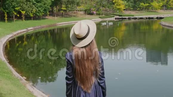 站在湖边享受大自然的草帽女人的后景视频的预览图