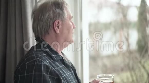 侧面的肖像体贴的高加索人看着窗外在室内喝茶孤独男视频的预览图