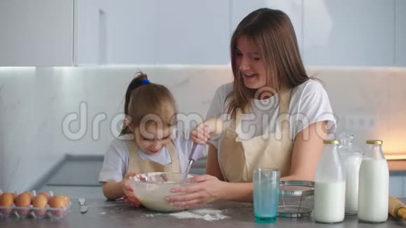 嘲笑妈妈和女儿在厨房做饭这个女孩向她母亲学习如何做馅饼快乐的童年视频的预览图