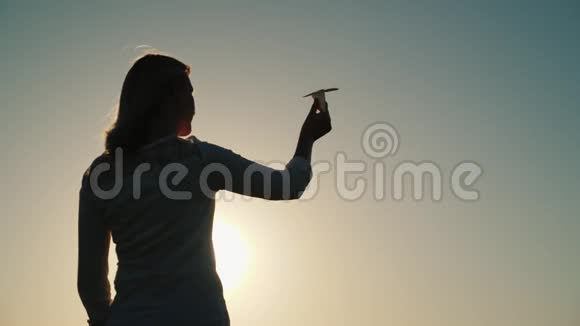 一个女人正在玩纸飞机它站在夕阳的光线下关于假期和旅行的梦想视频的预览图