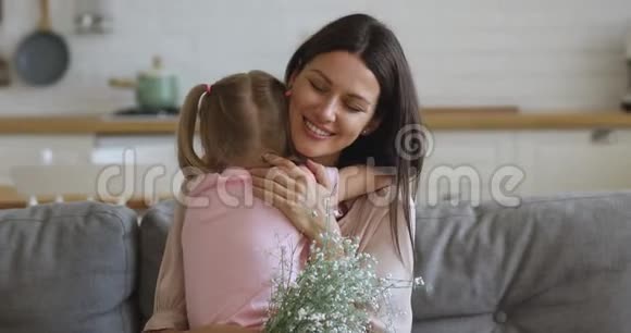 真诚的年轻母亲拥抱着幼小的学龄前女儿视频的预览图