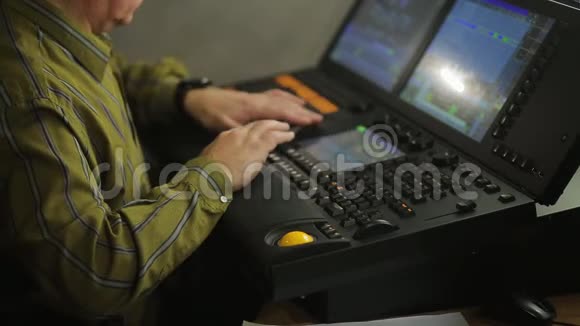 控制台的一名男性照明程序员正在为表演编程舞台灯光视频的预览图