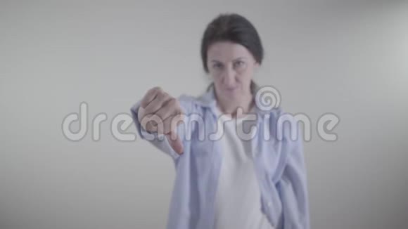 女性手的特写显示拇指向下白种人模糊的女人在后台摇头表示不视频的预览图