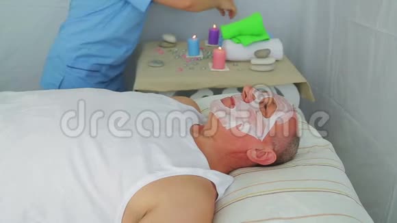 女性美容师在男人脸上做蔬菜疗法视频的预览图